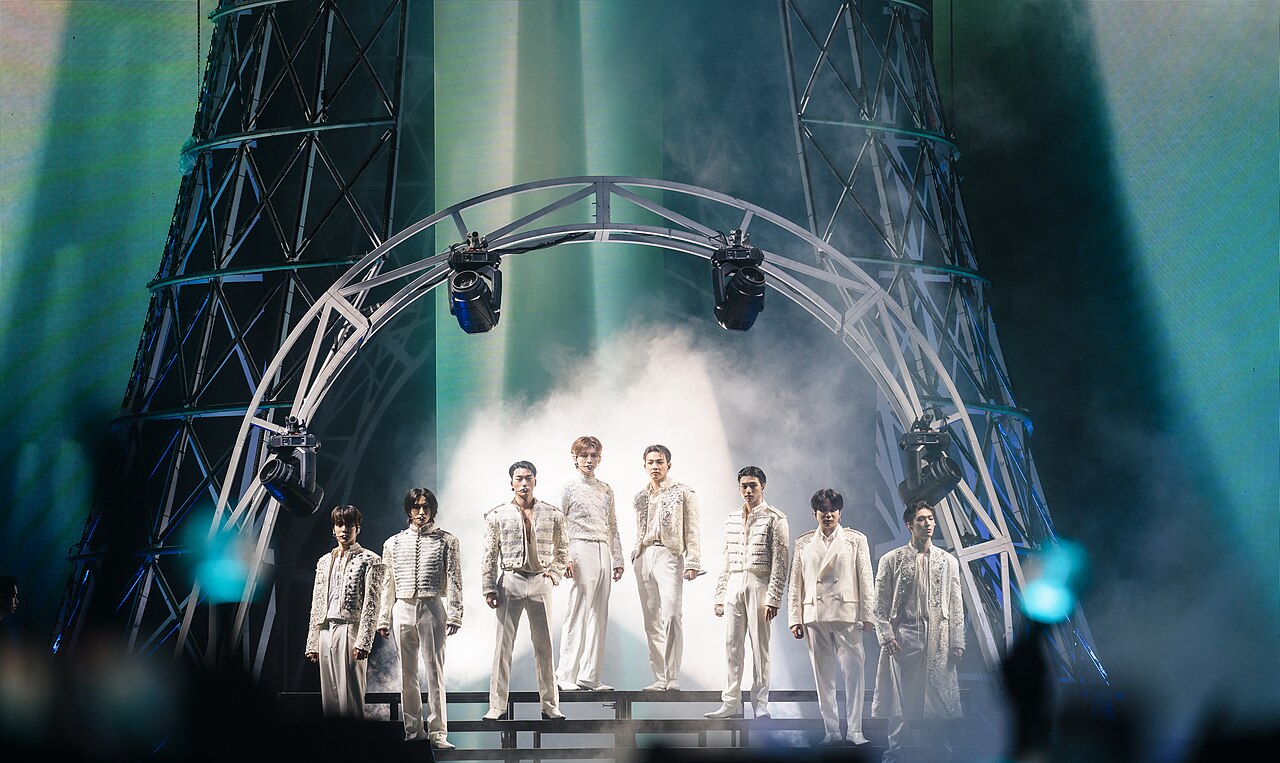 All eight ATEEZ members in white stage outfits performing on their Towards the Light world tour in New York, August 2024